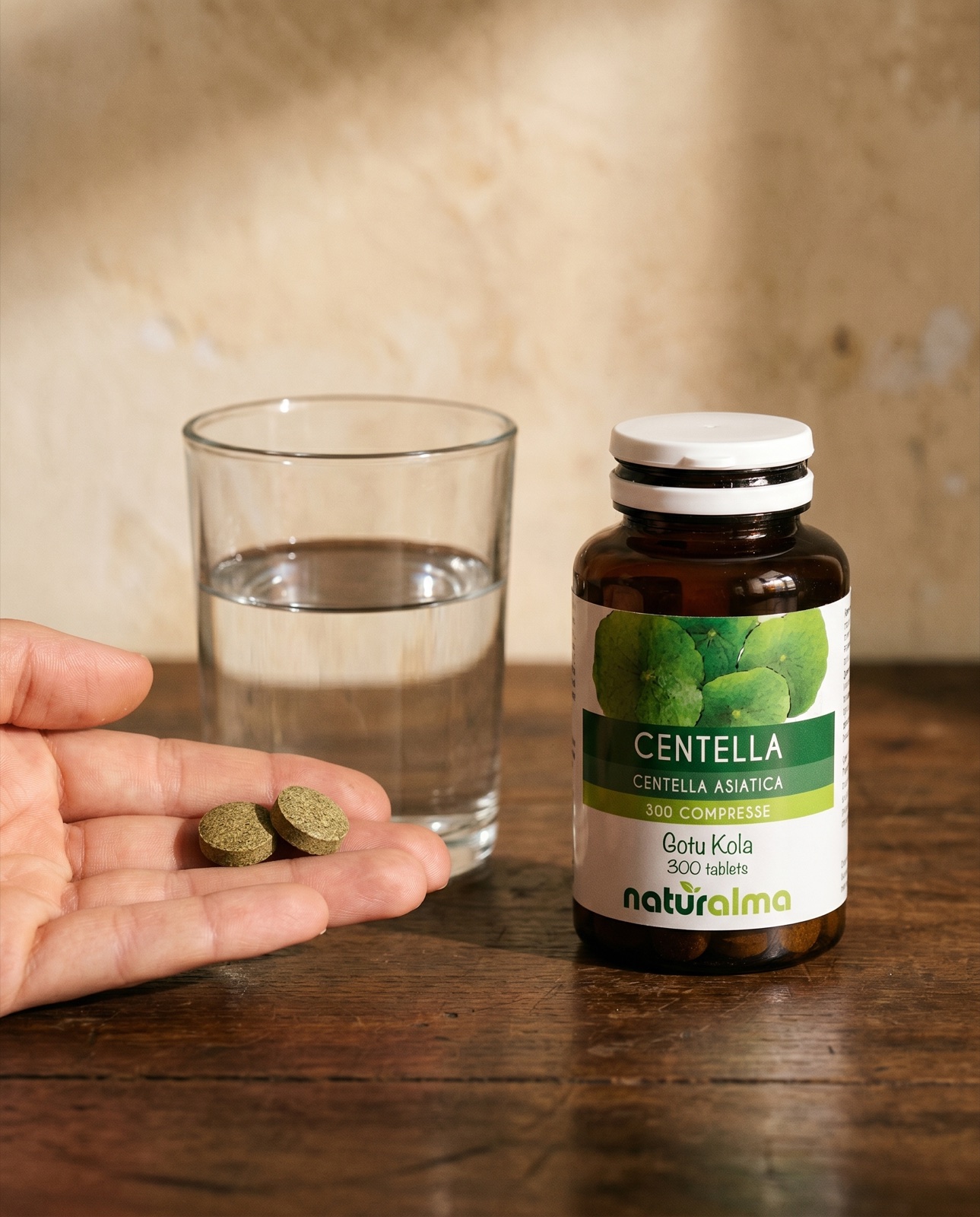 Centella asiatica — mano con due compresse, un bicchiere d'acqua e il barattolo Naturalma