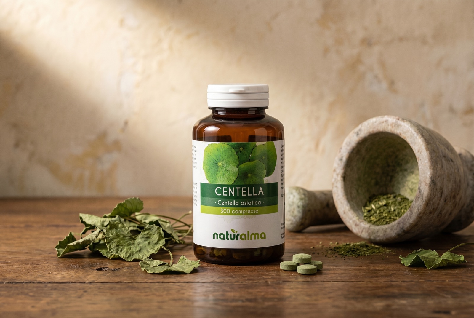 Centella asiatica — still life con foglie tonde a ventaglio e barattolo di compresse Naturalma